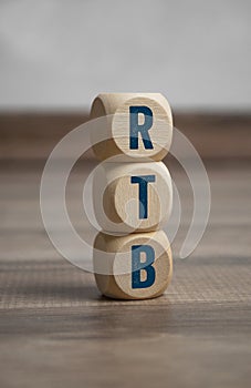 Tower made of cubes and dice with acronym RTB - Real Time Bidding - on wooden background