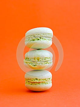 tower of mint green pastel macarons close-up on bright orange background