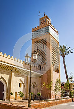 Tower of mosque minaret at medina quarter of Marrakesh, Morocco. There are walls and palms. It is a Badi palace