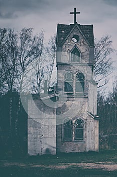 The tower of an old abandoned Church against a cloudy stormy sky. Beautiful background for greeting card or wallpaper on Halloween