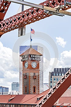 The tower of the old railway station against the backdrop of a modern skyscraper through the trusses of the Broadway bridge in