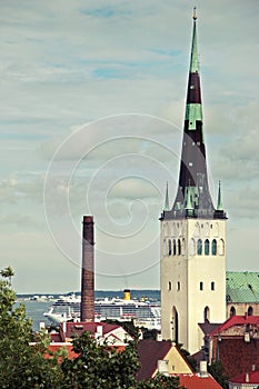 Tower Oleviste in the old city of Tallinn against the sky and the ferry in the background.