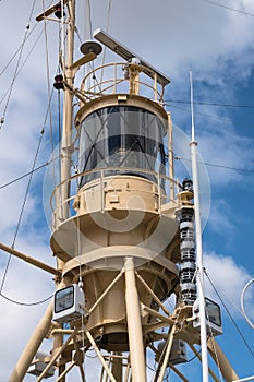 tower of a rescue ship with radar, lights and communication equipment against the blue sky with clouds, vertical