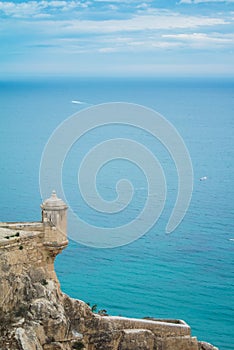 A tower of Santa Barbara castle al Alicante and a seascape of Mediterranean sea and a lonely ship