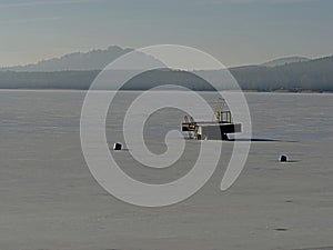 Tower of sliding track in frozen lake, icy water level. Winter tim