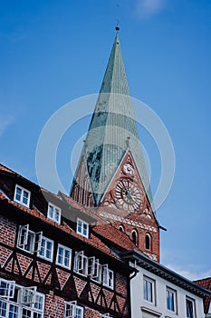 Tower of the St. Johannis church of Luneburg and an old half-timbered red bricks house in front. Germany