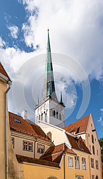 Tower of St Olaf's Church behind traditional buildings in old town of Tallinn, Estonia.