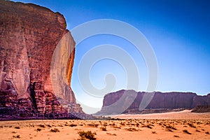 Towering cliffs of red, rocky outcrops among the vast orange desert sands of Wadi Rum