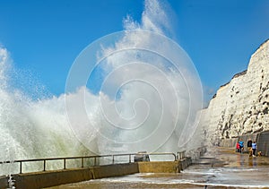 Towering crashing waves next to seaside walkers at Rottingdean,England