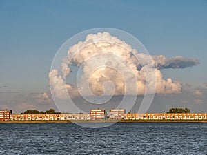 Towering cumulonimbus cloud over apartments on IJsselmeerdijk in Lelystad, Netherlands