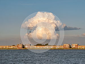 Towering cumulonimbus cloud over apartments on IJsselmeerdijk in Lelystad, Netherlands