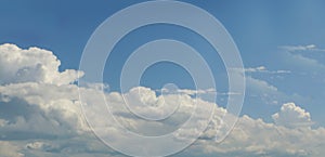 Towering fluffy clouds building in big blue sky - horizontal background