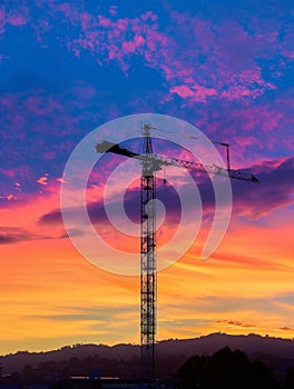 The towering structure of a construction crane stands out against the twilight sky, showcasing industrial progress.