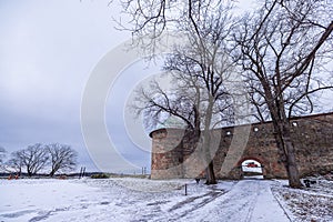 Towers of Akershus castle in Oslo. Cannon on the embankment, tower from brick visible. Cloudy weather in winter, snow lying around