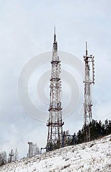 Towers or antennas of cellular communication 4G and 5G or television broadcasting against a cloudy sky on a mountain, winter