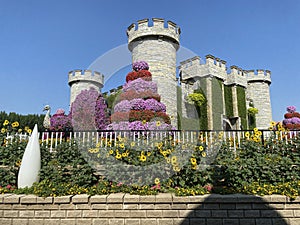 Towers in castle covered by plants and flowers, amazing colorful park, Miracle garden in Dubai