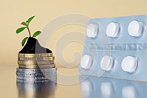 Towers from coins with plant and pills - Medical business concept.