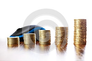 Towers of coins on wooden table in front of computer mouse