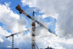 Towers cranes against a partly cloudy blue sky