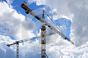 Towers cranes against a partly cloudy blue sky