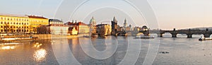 Towers of Prague Old Town and Charles Bridge over Vltava River illuminated by sunset. Panoramic view.