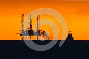 Towing of the oil platform. Oil platform at sunset with a burning torch. Drilling platform in the port