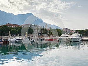 The town of Baska Voda in Croatia. View of the marina, promenade with palm trees and Biokovo Mountain