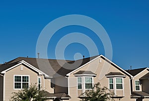 Townhome rooftops in the suburbs under a blue sky.