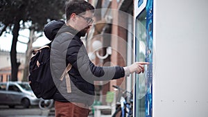 Townsman presses buttons on street vending machine