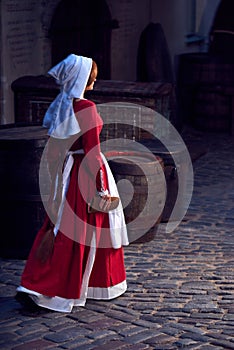 Townswoman in red dress with an apron and chaperone on the street. photo
