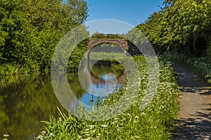 A towpath leading to a bridge and reflection on the Grand Union Canal near to Great Bowden