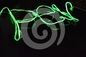 Toxic green lime lighting with a specific pattern. Woven filaments, cable, wires with outgoing light. Neon electroluminescent wire