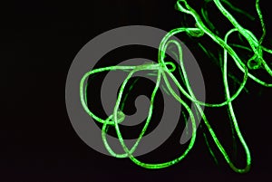 Toxic green lime lighting with a specific pattern. Woven filaments, cable, wires with outgoing light. Neon electroluminescent wire