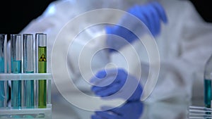 Toxic laboratory analyst putting tube with ionizing radiation liquid into holder