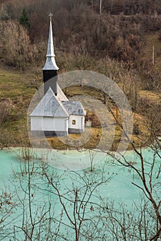 Toxic waste waters from a copper and gold mine submerge village. Abandoned orthodox church on lakeside