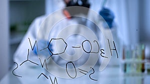 Toxicologist compounding biochemical liquids in test tube, formula on foreground