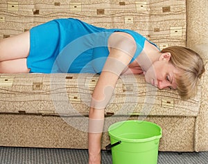 Toxicosis. The pregnant woman lies on a sofa with a bucket photo