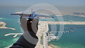 Toy aircraft flies against the backdrop of Palm Jumeirah Island in Dubai. The concept of travel.