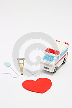 Toy ambulance car and abstract red heart on white background.