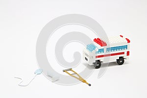 Toy ambulance car, miniature drop, gibbs, and crutch on white background.