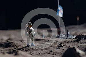 The toy of the astronaut stands on the moon's surface