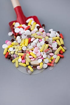 Toy baby scoop full of multi-colored pharmaceutical pills and capsules