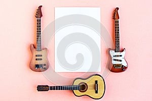 Toy bass, acoustic and electric guitars and white mockup blank on pink background