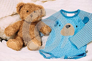 Toy Bear Near Child`s Clothes Rompers.