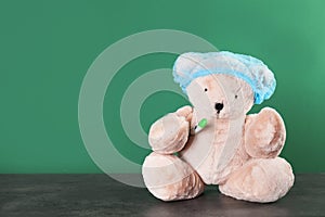Toy bear with thermometer on table against color background. Children`s hospital