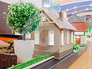 Toy beige house with a decorative lawn and a tree in a white pot