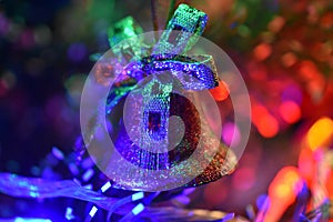 Toy bell on the background of bright festive lights, blurred image