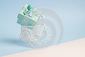 A toy bike carries a gift. The idea for a postcard. Blue background. Minimalism