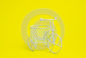 A toy bike. The idea for a postcard. Yellow background. Minimalism