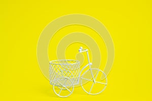 A toy bike. The idea for a postcard. Yellow background. Minimalism